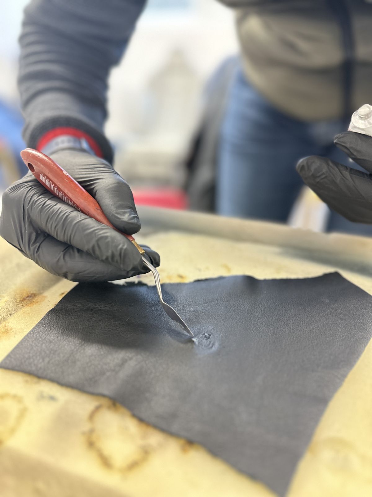 Application de mastic à la spatule sur un cuir noir